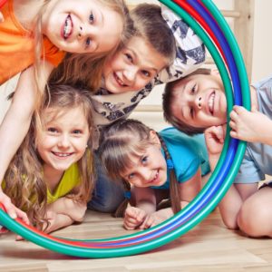 Five cheerful kids looking through hula hoops